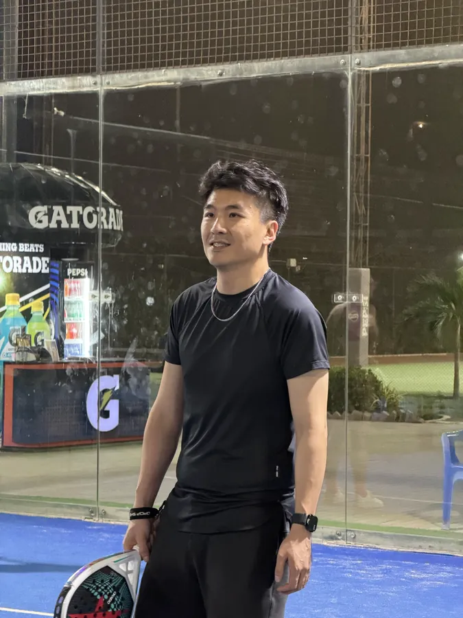 Kelvin on a padel court at night, holding a padel racket